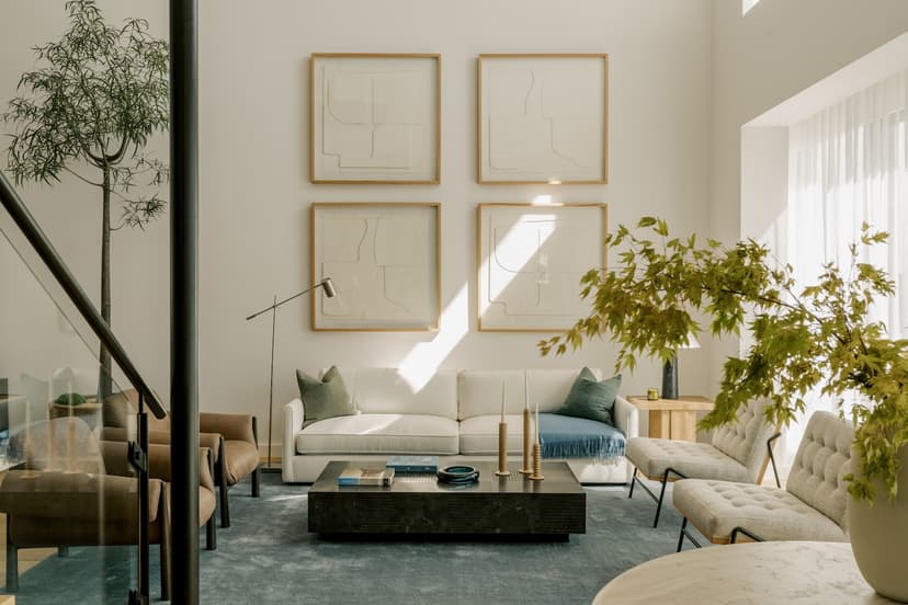 Bright, modern living room interior with a plush sofa, coffee table with décor, accent chairs, ambient lighting, and large windows that let in natural light, reflecting contemporary luxury residential design.