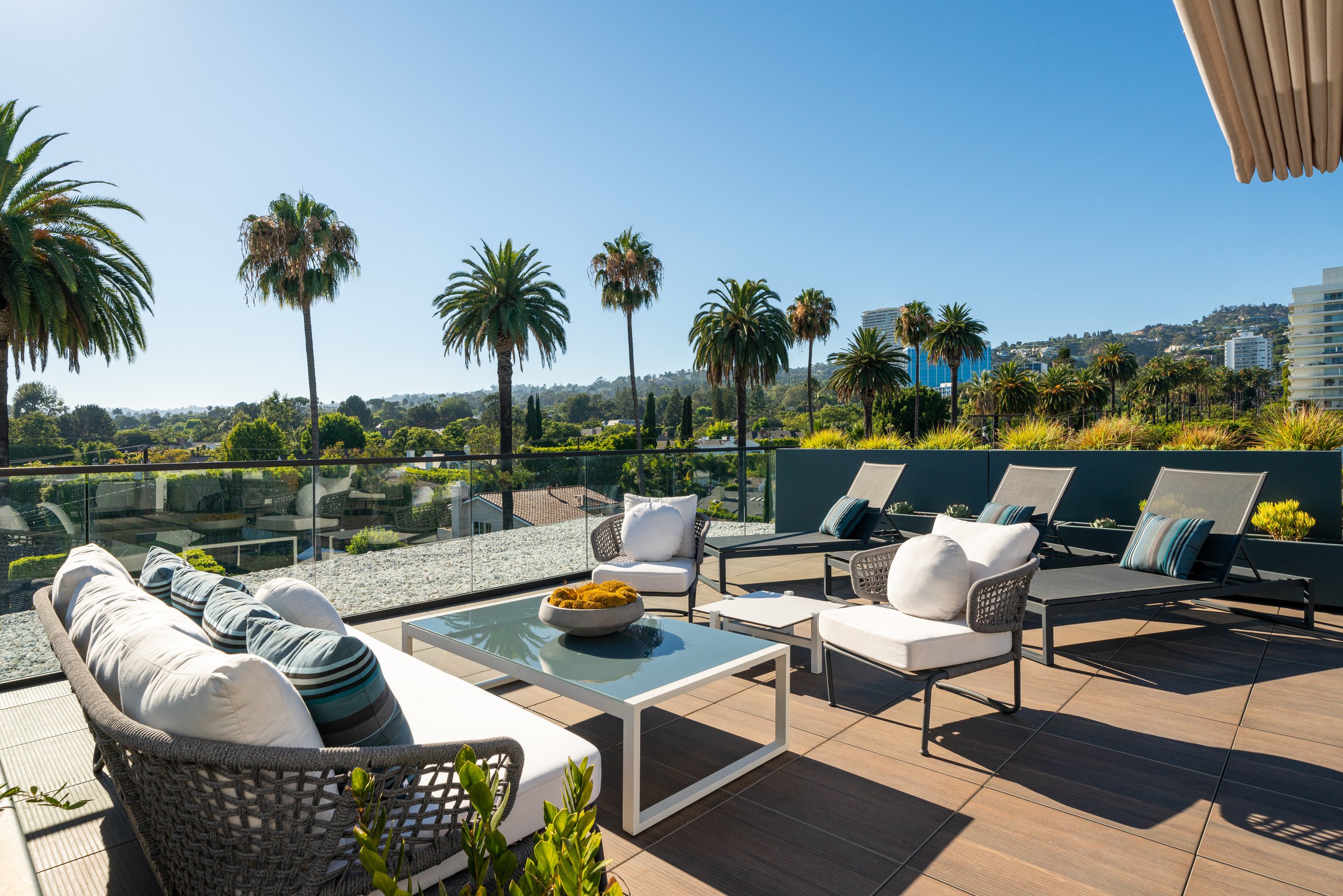 A photo of a rooftop terrace on a sunny day with vast, unobstructed views of Los Angeles